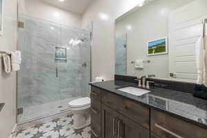 Bathroom with tile floors, an enclosed shower, toilet, and vanity