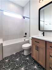 Full bathroom featuring tile floors, vanity, toilet, and tiled shower / bath
