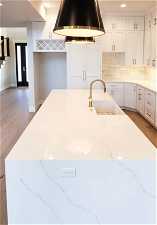Kitchen with white cabinets, light hardwood / wood-style flooring, and sink
