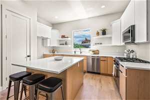Kitchen featuring a center island, light hardwood floors, a kitchen bar, appliances with stainless steel finishes, and sink