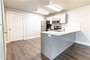 Kitchen with sink, dark hardwood flooring, tasteful backsplash, stainless steel appliances, and kitchen peninsula