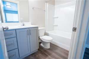 Full bathroom featuring toilet, hardwood flooring, washtub / shower combination, and vanity