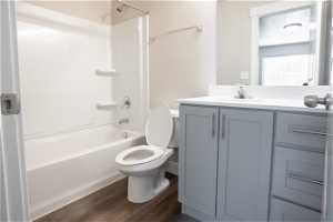 Full bathroom with toilet, hardwood flooring, oversized vanity, and shower / bathtub combination
