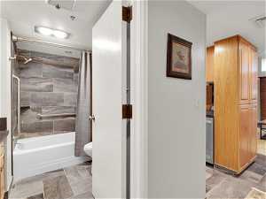 Full bathroom featuring shower / bath combination with curtain, vanity, tile floors, and toilet
