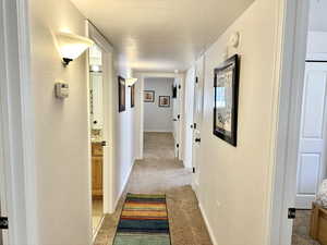 Corridor with light colored carpet and a textured ceiling