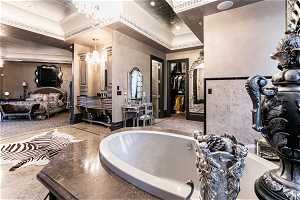 Bathroom with a bath to relax in, a notable chandelier, vanity, crown molding, and a tray ceiling