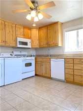 Kitchen featuring white appliances, washing machine and dryer, light tile floors, and ceiling fan