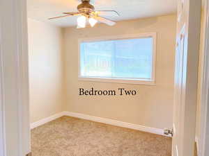 Carpeted empty room featuring ceiling fan