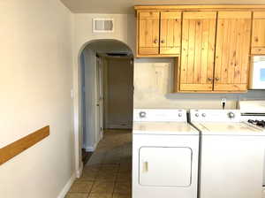 Clothes washing area with dark tile floors and washer and dryer in the kitchen.