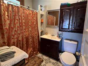 Bathroom with tile flooring, backsplash, toilet, and oversized vanity