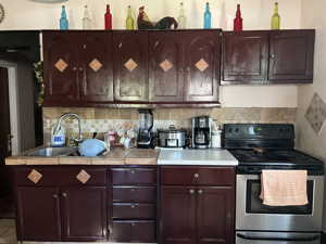 Kitchen featuring stainless steel electric stove, tasteful backsplash, and sink