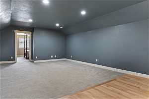 Additional living space with vaulted ceiling and light carpet