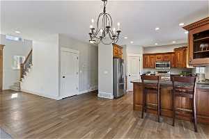 Kitchen with light wood-type flooring, a notable chandelier, and appliances with stainless steel finishes
