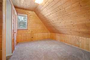 Bonus room featuring light carpet, lofted ceiling, wood walls, and wooden ceiling