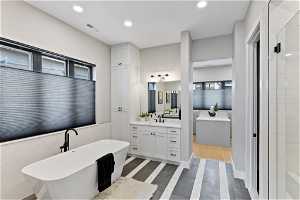 Bathroom with tile walls, a washtub, large vanity, and tile floors
