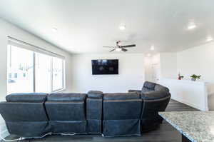 Living room featuring ceiling fan, dark hardwood / wood-style floors, and a textured ceiling