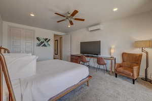 Bedroom featuring light carpet, an AC wall unit, and ceiling fan