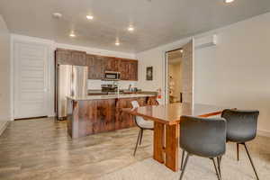 Kitchen featuring sink, a breakfast bar area, light tile floors, a kitchen island with sink, and appliances with stainless steel finishes