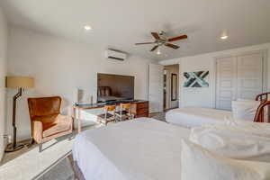 Carpeted bedroom with a closet, ceiling fan, and a wall mounted air conditioner