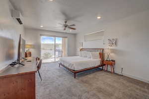 Bedroom featuring access to exterior, ceiling fan, light colored carpet, and an AC wall unit