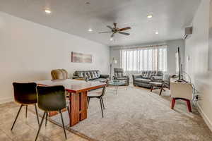 Interior space featuring ceiling fan, light tile floors, and an AC wall unit