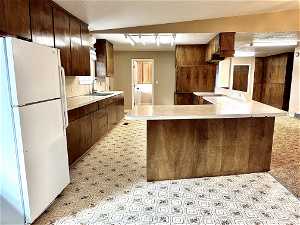 Huge kitchen featuring sink, light tile floors, white refrigerator, and kitchen peninsula