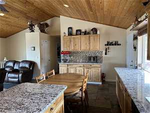 Kitchen with light brown cabinets, tasteful backsplash, dark tile floors, lofted ceiling, and wooden ceiling