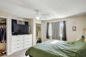 Carpeted bedroom featuring a closet, ceiling fan, and a textured ceiling