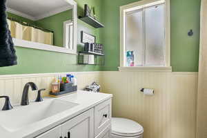 Bathroom featuring large vanity, toilet, and ornamental molding