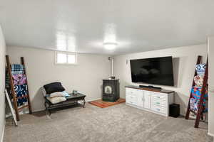 Carpeted living room featuring a wood stove and a textured ceiling