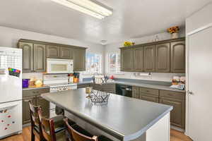 Kitchen featuring a kitchen bar, a kitchen island, a textured ceiling, light wood-type flooring, and white appliances