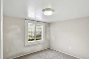 Carpeted spare room with a textured ceiling