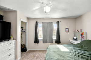 Carpeted bedroom with a closet, ceiling fan, and a textured ceiling