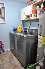 Clothes washing area with electric water heater, washing machine and clothes dryer, cabinets, and light tile floors