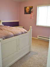 Unfurnished bedroom featuring baseboard heating and light colored carpet