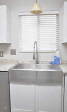 Kitchen featuring sink, decorative light fixtures, light stone counters, and white cabinets