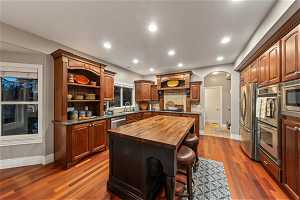 Kitchen featuring a center island, sink, dark hardwood / wood-style flooring, a kitchen breakfast bar, and wood counters