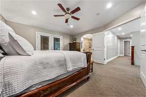 Carpeted bedroom with connected bathroom, ceiling fan, and french doors