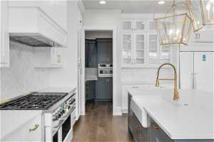 Kitchen featuring custom exhaust hood, white cabinets, tasteful backsplash, high end appliances, and dark hardwood / wood-style floors