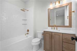 Full bathroom with oversized vanity, tiled shower / bath, toilet, and tile floors