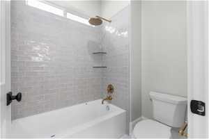 Bathroom featuring tiled shower / bath combo and toilet