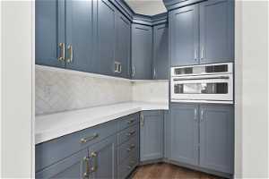 Kitchen featuring backsplash, dark hardwood / wood-style floors, blue cabinetry, and oven