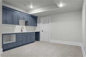 Kitchen featuring light carpet, sink, blue cabinetry, and a textured ceiling