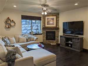 Living room featuring dark hardwood / wood-style floors, ceiling fan, and a stone fireplace