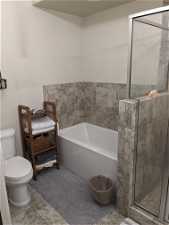 Bathroom featuring toilet, tile flooring, and independent shower and bath