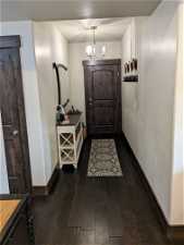Doorway to outside with dark hardwood / wood-style floors and a chandelier