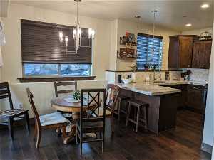 Kitchen featuring dark brown cabinets, tasteful backsplash, pendant lighting, and a chandelier