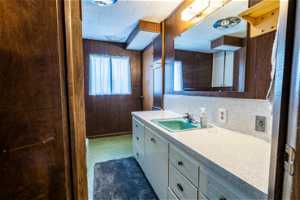 Bathroom featuring tile flooring, tasteful backsplash, wooden walls, and vanity