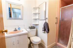 Primary bathroom featuring toilet, tile floors, a shower with shower door, and oversized vanity
