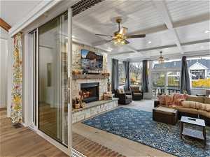 Sunroom with light hardwood / wood-style floors, ceiling fan, a stone fireplace, and beamed ceiling